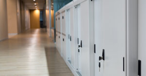 Select focus for key. White Cabinet for document storage. The keys are plugged into the filing cabinet. The filing cabinet is located on the floor beside the walkway.