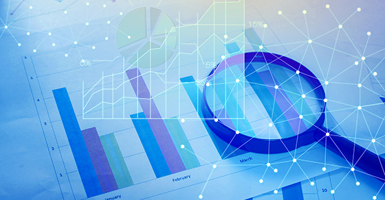 Magnifying glass and documents with analytics data lying on tabl